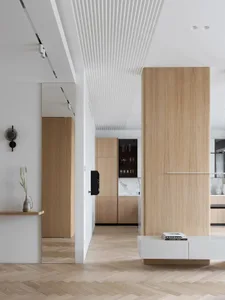 Modern residential kitchen with white cabinets, marble countertops, and wood flooring.