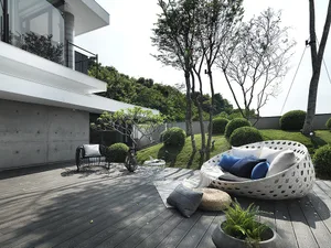 Modern outdoor living space with a concrete deck, comfortable seating, and greenery around.