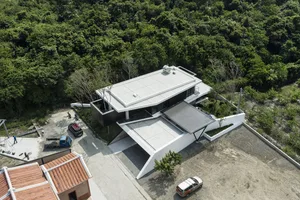 A modern residential home with white and glass exteriors surrounded by trees.