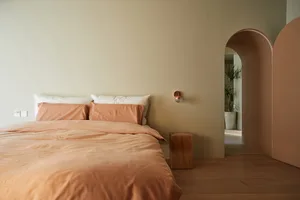 A contemporary bedroom with wooden furniture and peach-colored bedding.