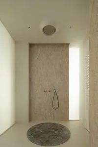 Modern minimalist bathroom with a circular marble floor step and a wall-mounted shower head.