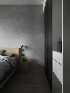 A minimalist bedroom with concrete walls and wooden furniture.