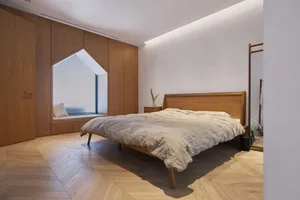 Minimalist bedroom with wooden furniture and light-colored bedding.