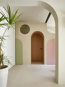 Architectural design featuring minimalist white walls with curved arches and potted plants.