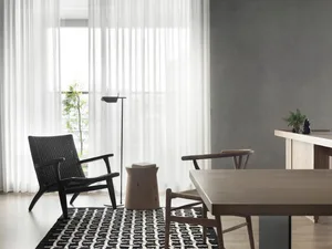 A minimalist living room featuring wooden furniture and a patterned rug.