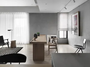 A modern home office with concrete walls, a wooden desk, and a glass window.