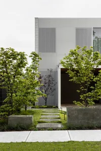 Modern house exterior featuring metal cladding and lush green plantings.