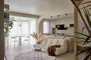 A modern living room with concrete flooring and fabric furniture, featuring a white sofa and a round coffee table.
