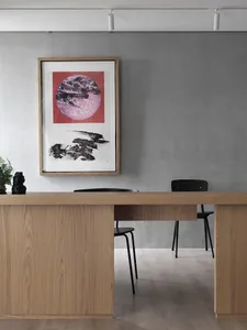 Modern office with a wooden desk and black chair, featuring a framed abstract artwork.