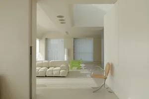 A modern white living room with a white sofa and green chairs.