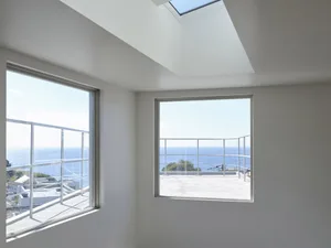 A minimalist interior with large windows showcasing glass materials and ocean views.