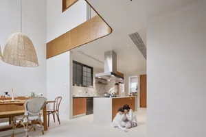 A modern, minimalist residential kitchen featuring concrete countertops, wooden cabinetry, and stainless steel appliances.