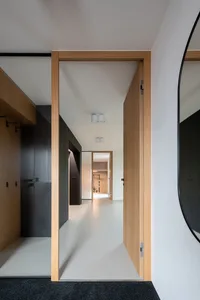 A modern interior corridor with light-colored hardwood floors and dark wooden cabinets.