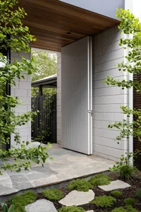 A modern entrance with concrete walls and a wooden roof structure.
