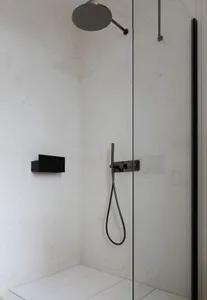 A modern bathroom with marble walls and floor, featuring a sleek black shower head and handheld shower.