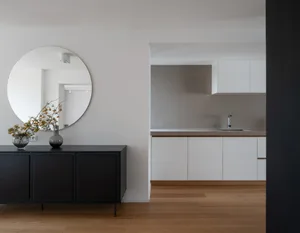 A modern minimalist kitchen with a concrete finish and white cabinets.