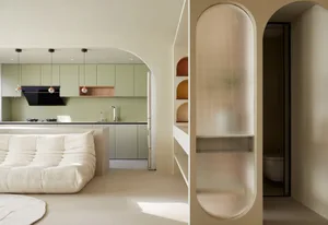 A modern minimalist kitchen with green cabinets, a white sofa, and a textured archway.