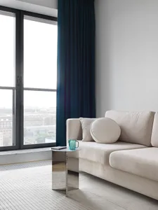 A minimalist living room with a cream-colored sofa and a small, metallic side table.
