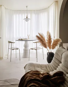 Modern living room with a beige couch, white curtains, and a hanging lamp