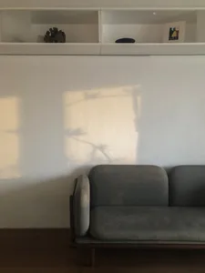 A modern neutral living room with a gray sofa and a wall-mounted shelf.