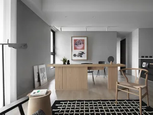 Modern office space featuring wooden desk and black furniture against a concrete wall, with a black and white geometric rug.