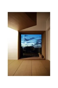 A modern living space featuring a wooden floor and a large window overlooking a cityscape during sunset.