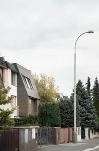 Street scene featuring a brick fence and a tall, white street lamp in an urban setting.
