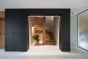 Minimalist interior design showcasing a wooden staircase with a potted plant and a sleek, modern atmosphere.