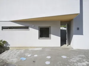 A minimalist residential entrance with white stucco walls and glass window and door.