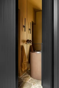 Modern bathroom with concrete walls and flooring, featuring a cylindrical sink and towel rack.