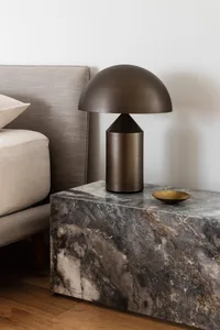 Modern bedroom featuring a marble nightstand with a stylish table lamp and a comfortable upholstered bed.