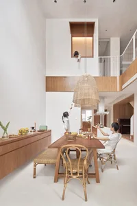 A modern dining room featuring wooden furniture and a hanging rattan pendant light.
