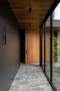 Modern entryway featuring a wooden door and stone flooring, showcasing contemporary design elements.
