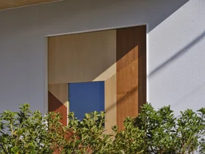 A modern exterior wall featuring a wood panel design with a blue glass insert.