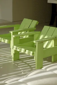 Two green wooden chairs in a modern interior setting.