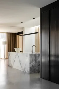 A modern kitchen with a marble countertop and white pendant lights.