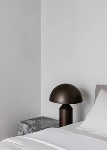 A minimalist bedroom featuring a modern metallic table lamp on a marble nightstand.