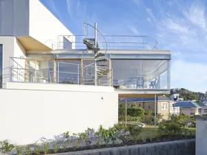 A modern residential exterior with glass walls and a spiral staircase.