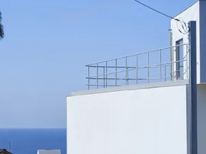 A modern white residential exterior with a concrete facade and white railings.