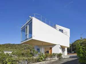 A modern house with a white exterior and large glass windows.