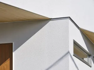 Modern exterior of a building with a white-rendered wall and wooden window trim.