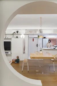 A modern residential interior featuring a minimalist design with white walls, wooden furniture, and glass elements.