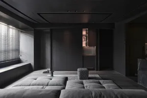 Modern minimalist living room with dark wood accents and leather seating, featuring dark metallic elements and a sleek, moder