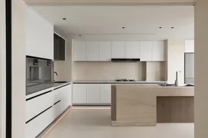 A modern, minimalist kitchen with sleek, white cabinetry and a central island.