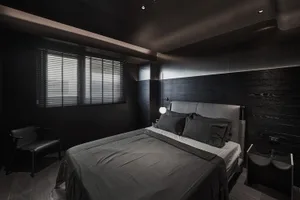 A modern bedroom with black walls, metal headboard, and wooden floor.