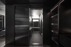 Modern bathroom featuring dark glass walls and floor, with a sleek design and minimalistic aesthetic.