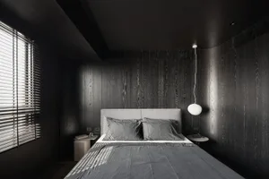 A modern bedroom with dark wood-paneled walls, a grey upholstered bed, and minimalistic decor.