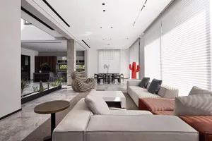 A modern living room with concrete and marble floors, large windows, and contemporary furniture, including a large white sofa