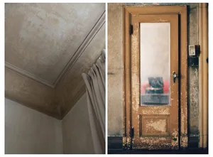 An old wooden door with a distressed paint finish, reflecting a chair.