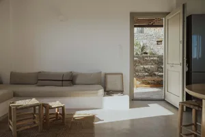 A modern, minimalist living room with concrete flooring, wooden furniture, and stone accents